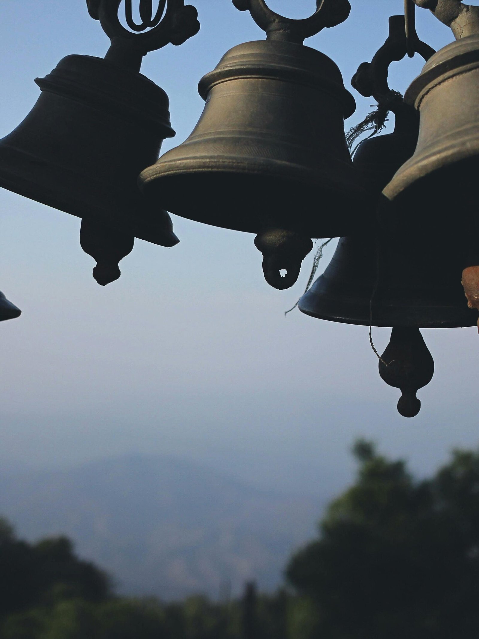 A collection of traditional hanging bells set against a scenic mountain backdrop, showcasing cultural heritage.